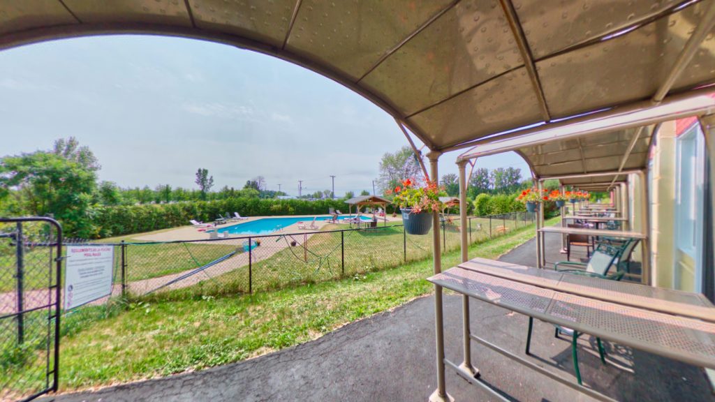 Private patio view of the outdoor seasonal pool at the Auberge Montebello Hotel overlooking the Montebello Marina in the distance.